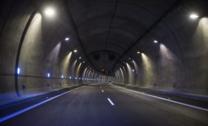 Dark concrete tunnel road illuminated by bright ceiling