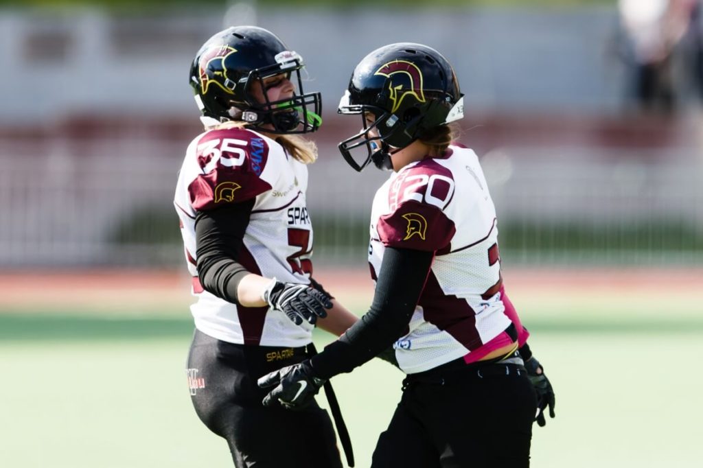 Female players in Spartan helmets celebrating on field.