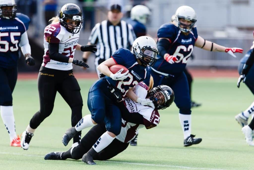 Female football players tackling during intense game action.