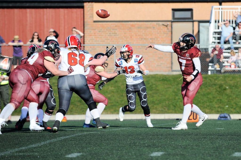 Female football players battling for an airborne pass.