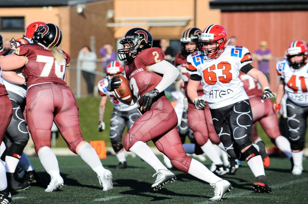 Female football runner carries ball past defenders quickly.