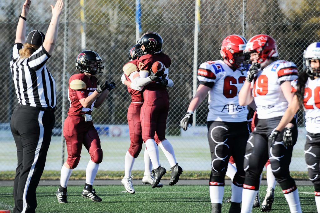 Referee signals score as football players hug cheering