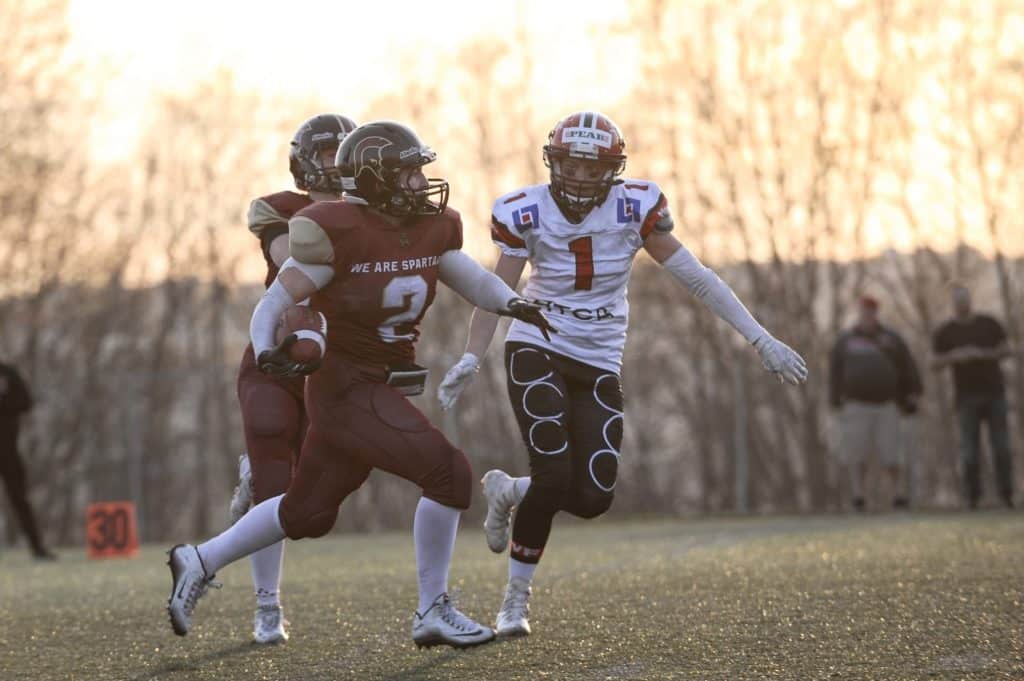 American football players running during golden hour practice.