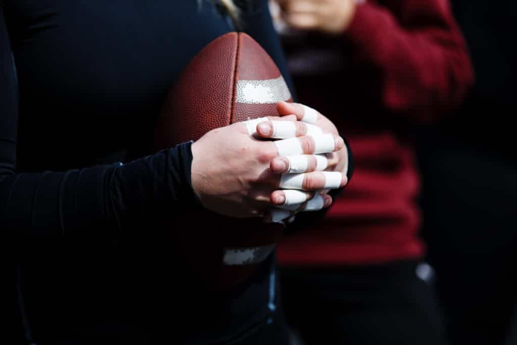 Athletes taped fingers clutch a leather football tightly.