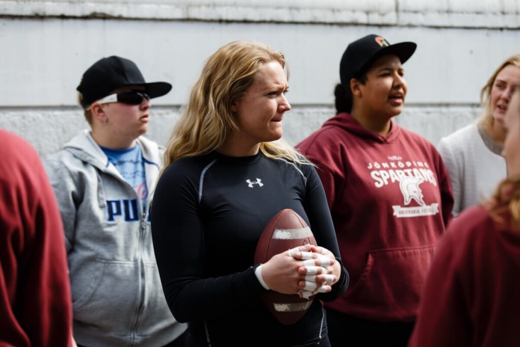 Female athlete holds football taped hands looking forward.