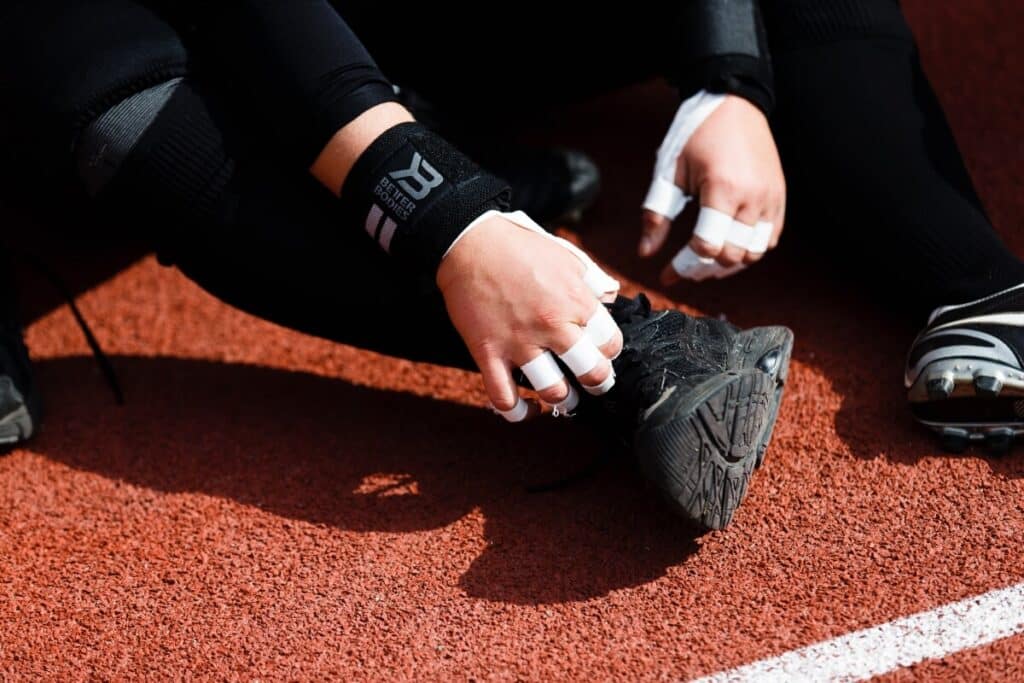 Athlete tying black shoe on red track surface