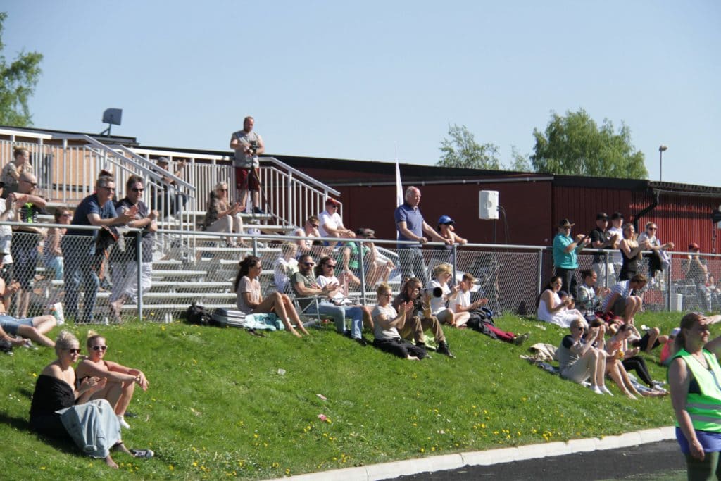 Crowd of spectators sitting on a grassy hill.