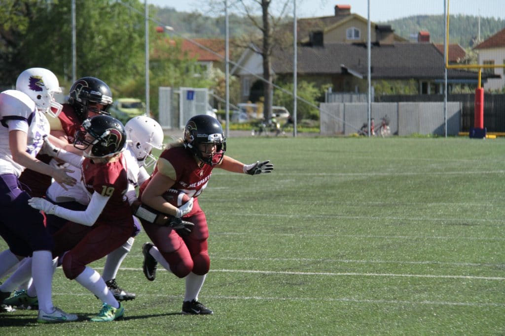 Maroon football player running with the ball outside