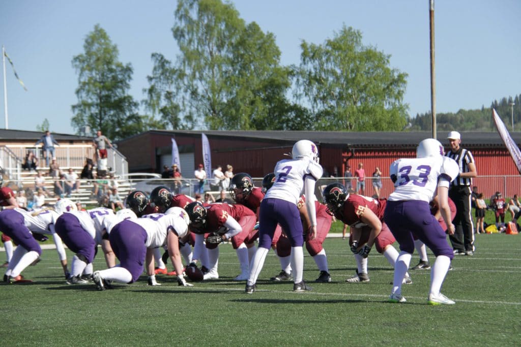 American football teams scrimmage outdoors on a green