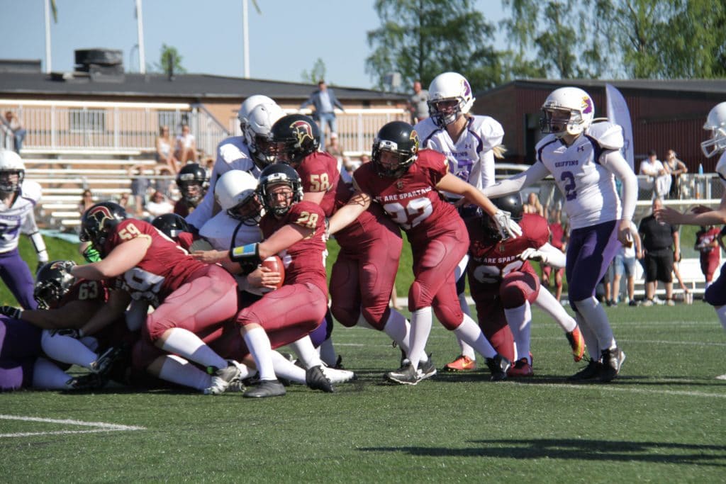 Maroon and white teams tackle during daylight game.