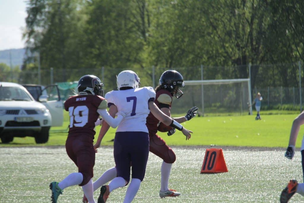 Football athletes running down sunny green sports field