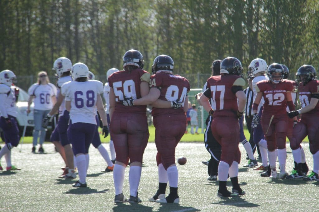 Football players in maroon and white jerseys huddle