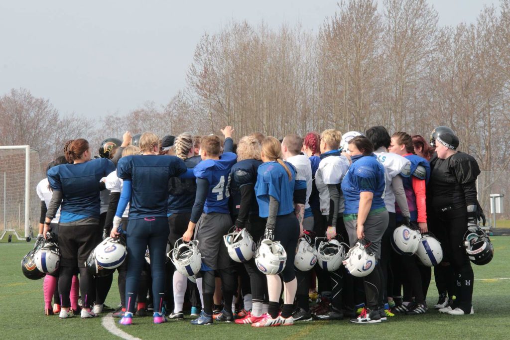 Blue jersey football players huddle holding white helmets