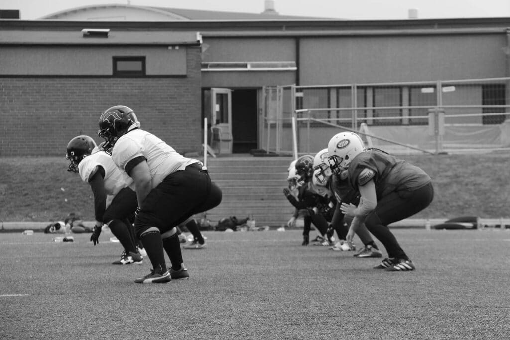 Black and white football players practicing on turf