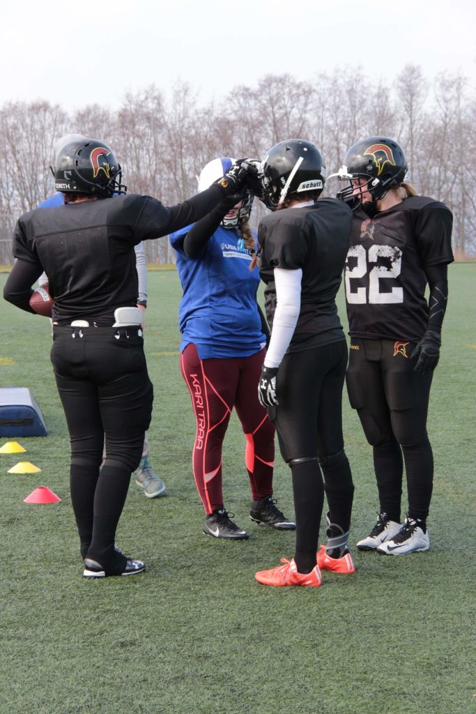 Black helmeted womens football team discussing strategy
