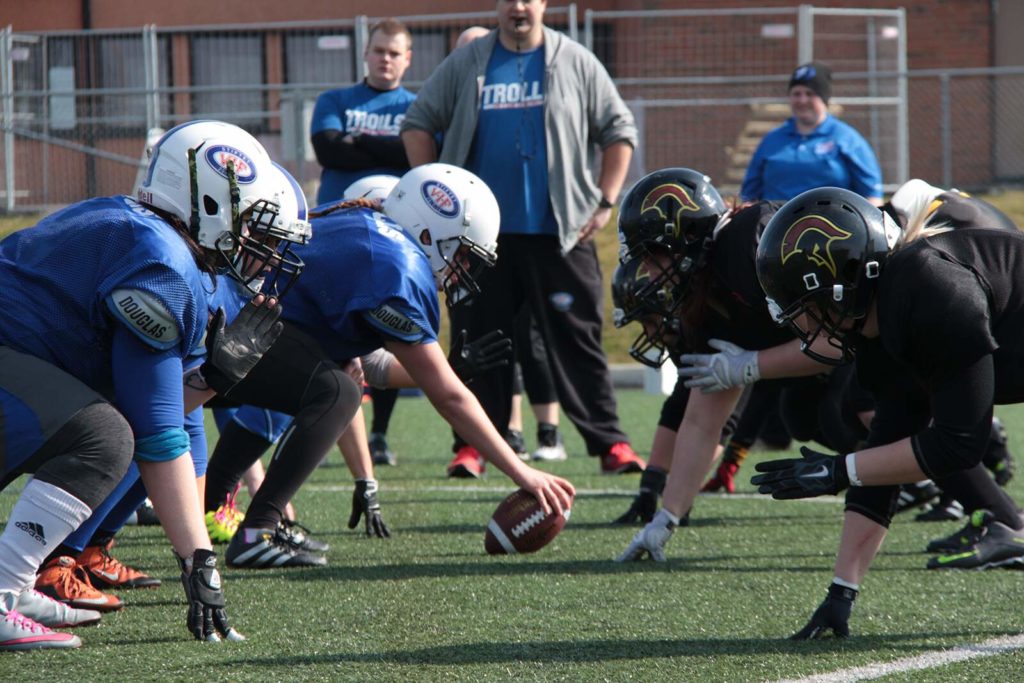 Athletes hiking football on green artificial turf field.
