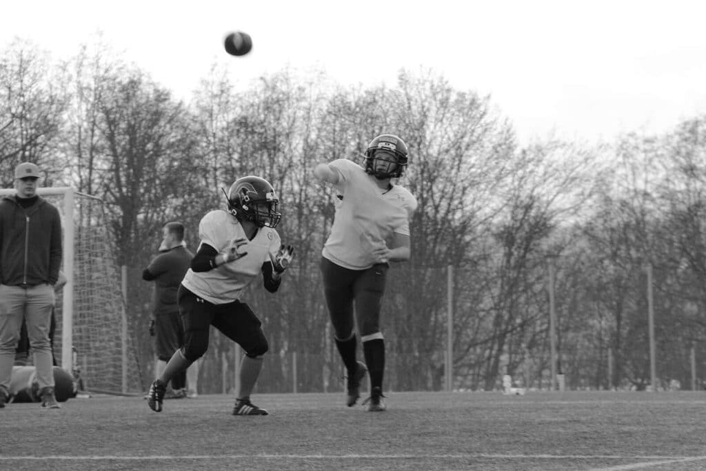 Black and white football players catching the ball.