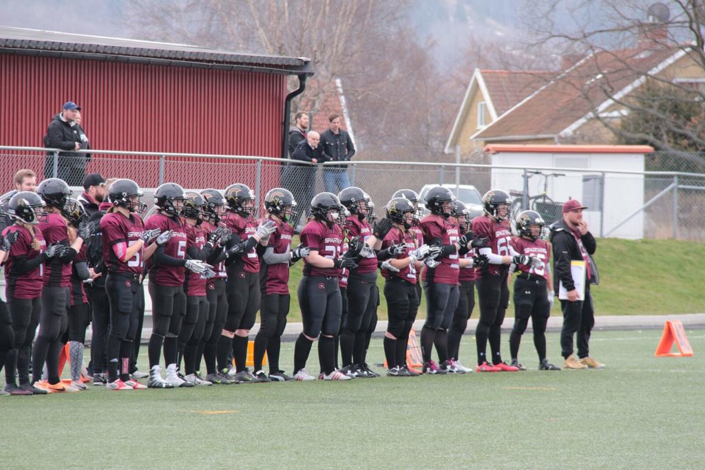 Maroon football team standing ready on green turf
