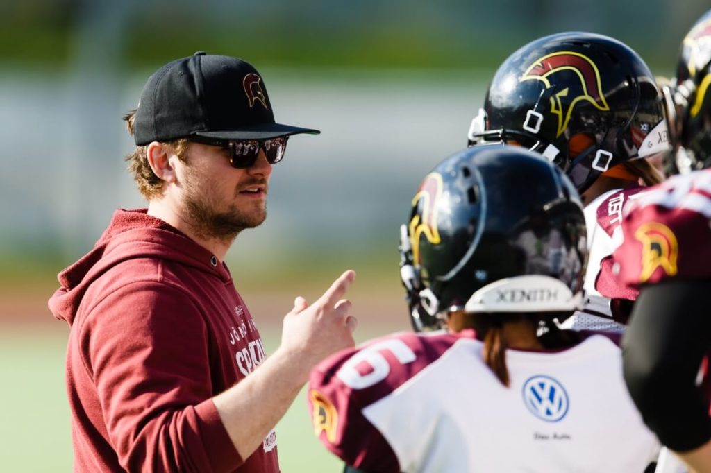 Coach instructs players wearing helmets on green field