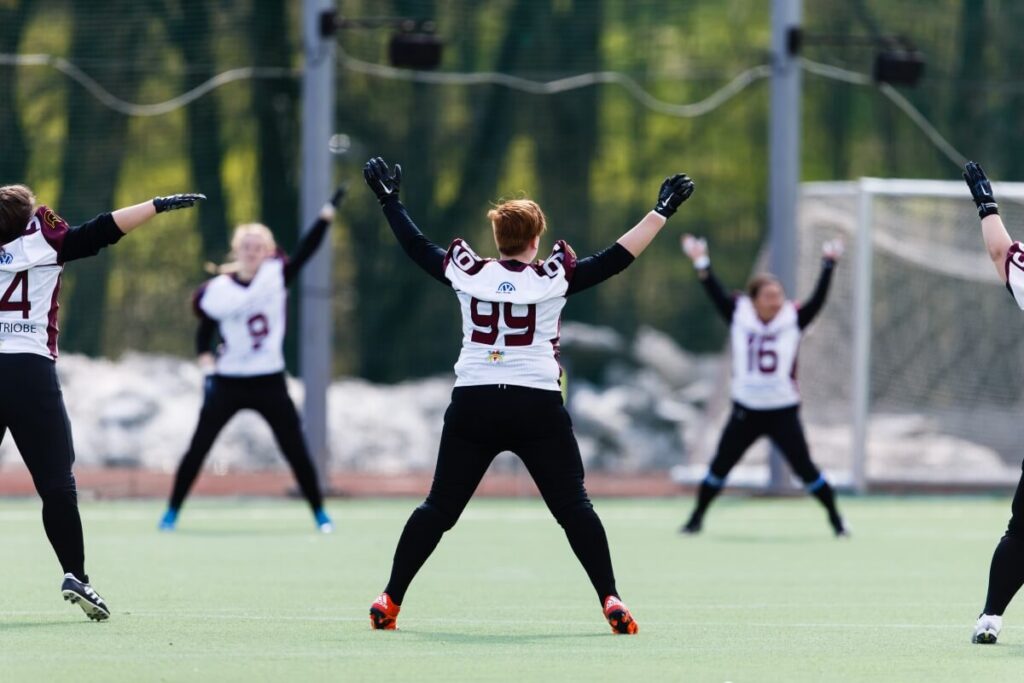 Female football players practice drills on green turf