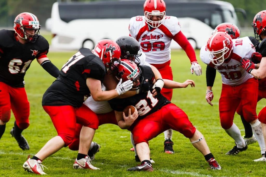 Red and black football teams tackle player with