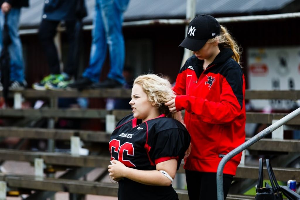 Girl fixing blonde teammates hair before game.