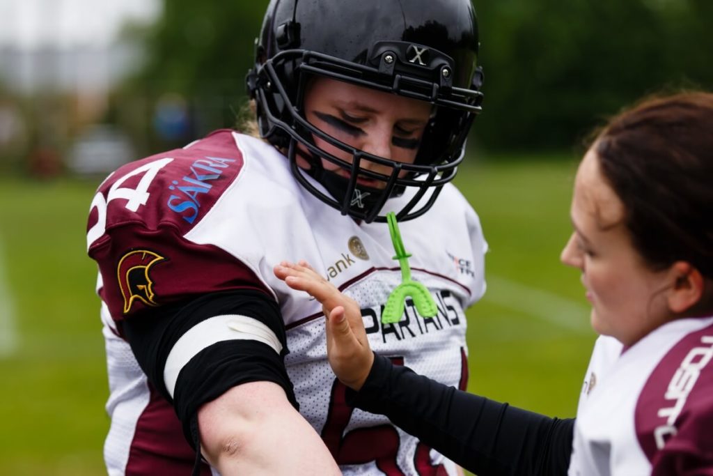 Female football player receiving sideline instructions outdoors.