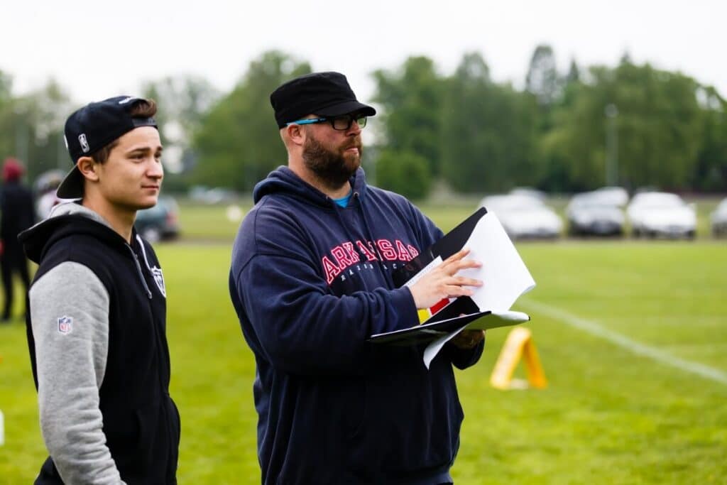 Coach reviewing notes with player on field