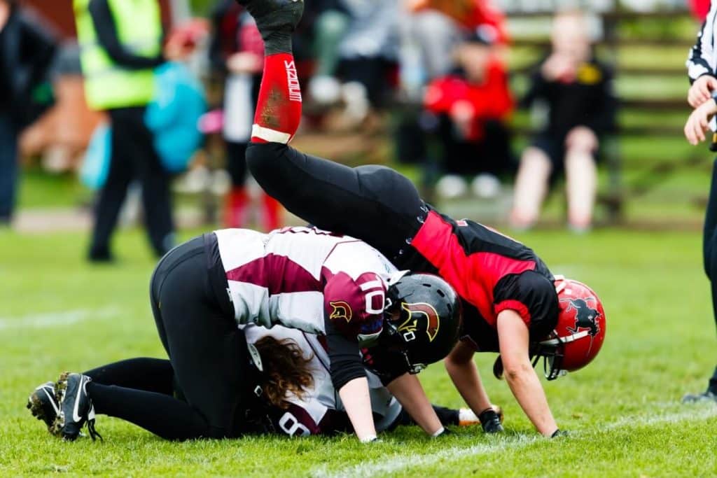 Women playing American football tackling fiercely on grass
