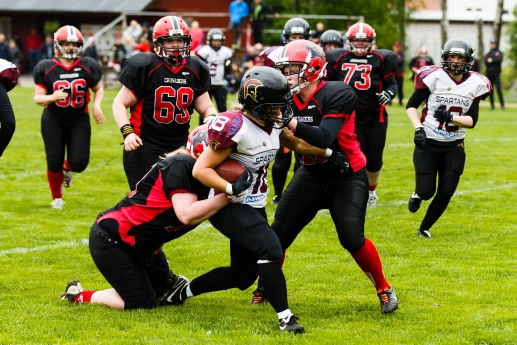Female football players tackling opponent on green field unique