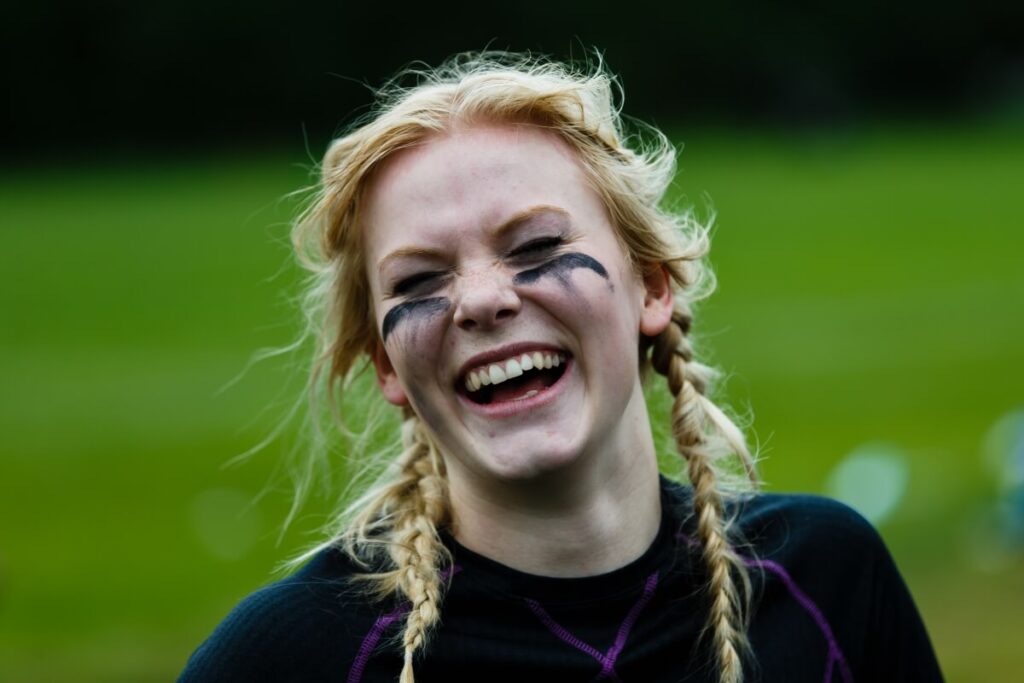 Young woman laughing with black athletic eye paint.