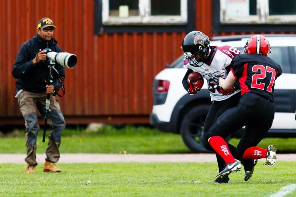 Action shot of football players and sideline photographer.