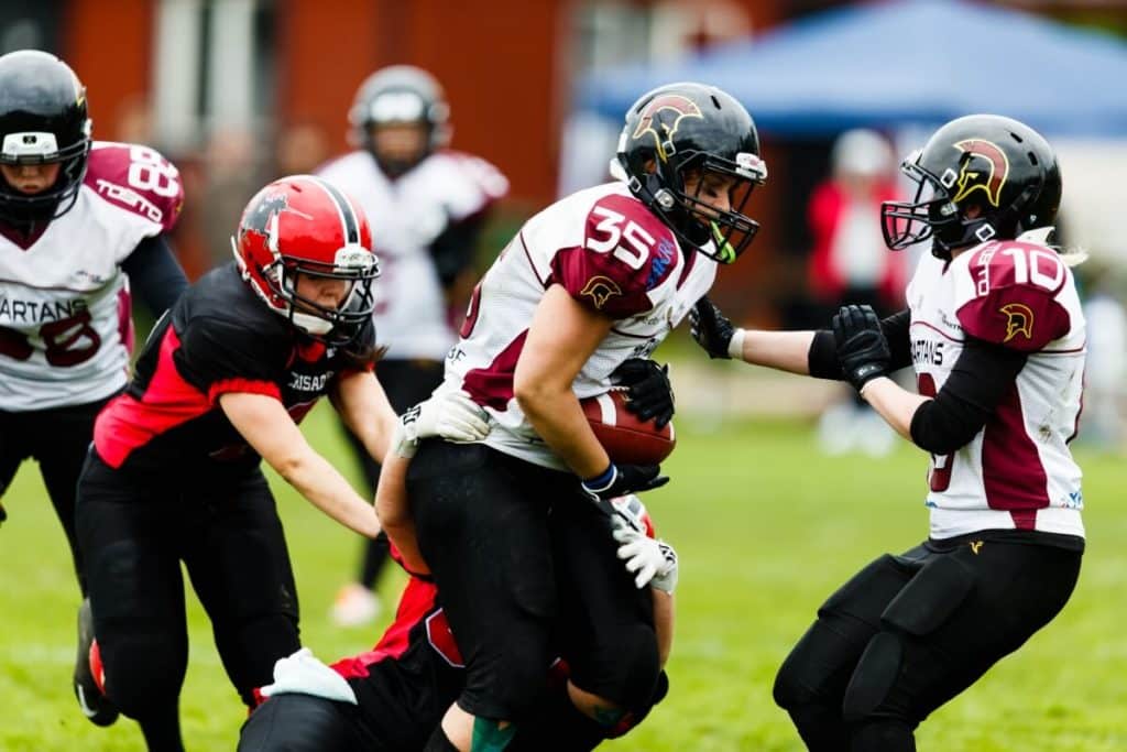 Women playing competitive American football tackling opponent
