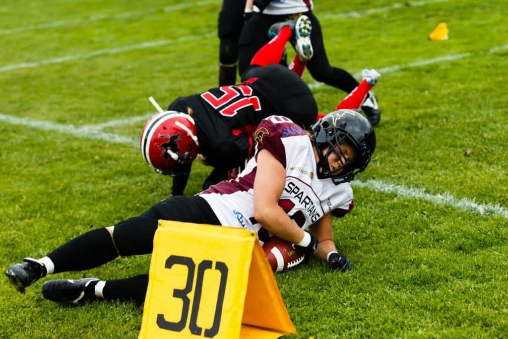 Intense womens football tackle on the field boundary.