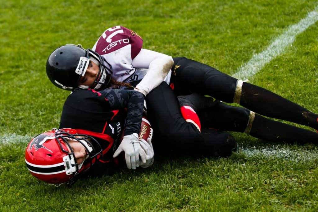 Female football players tackling hard on grassy field
