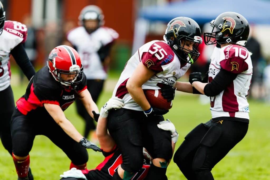 Female athletes tackling during intense football game outdoors.