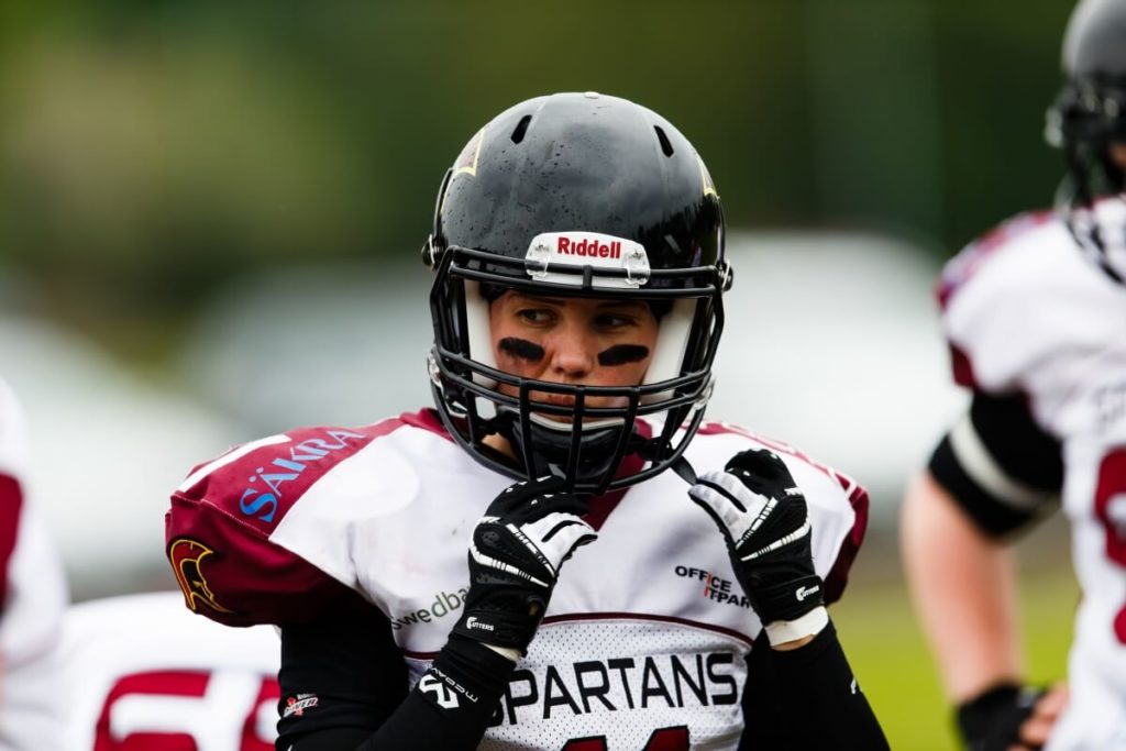 Football player adjusting helmet and gloves on field