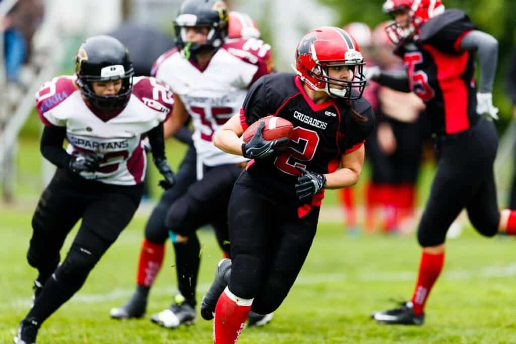 Black and red female football player running field