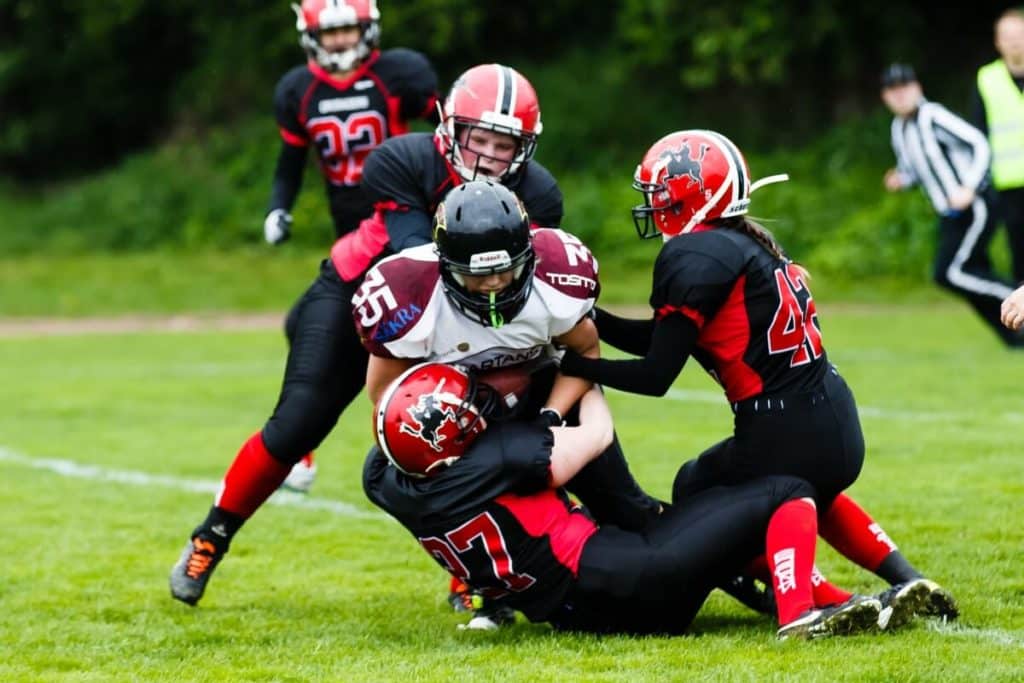 Players in red and black football uniforms tackling