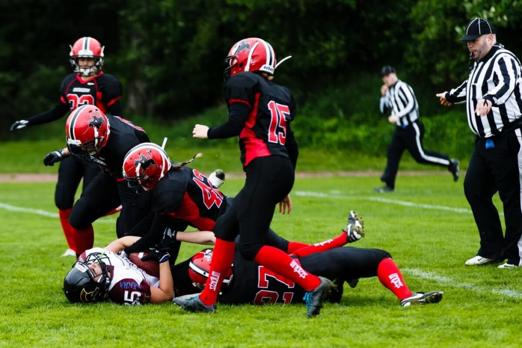 Female football players tackle opponent on green grass