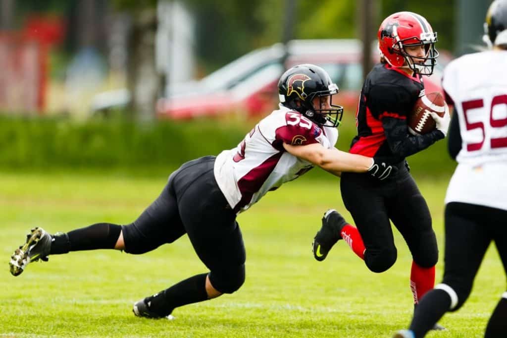 Female player running with football being tackled.