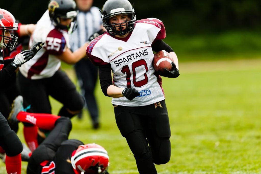 Determined female football player sprints with the ball.
