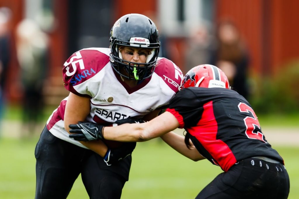 Two female athletes fiercely battle playing football