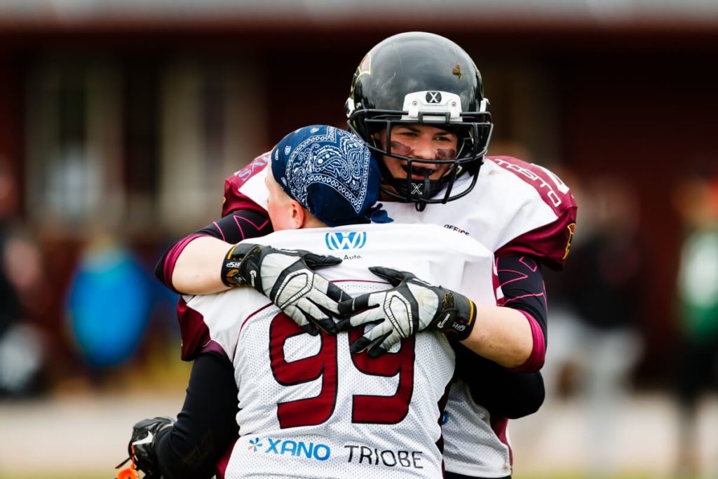 Two football players embrace celebrating on the field.