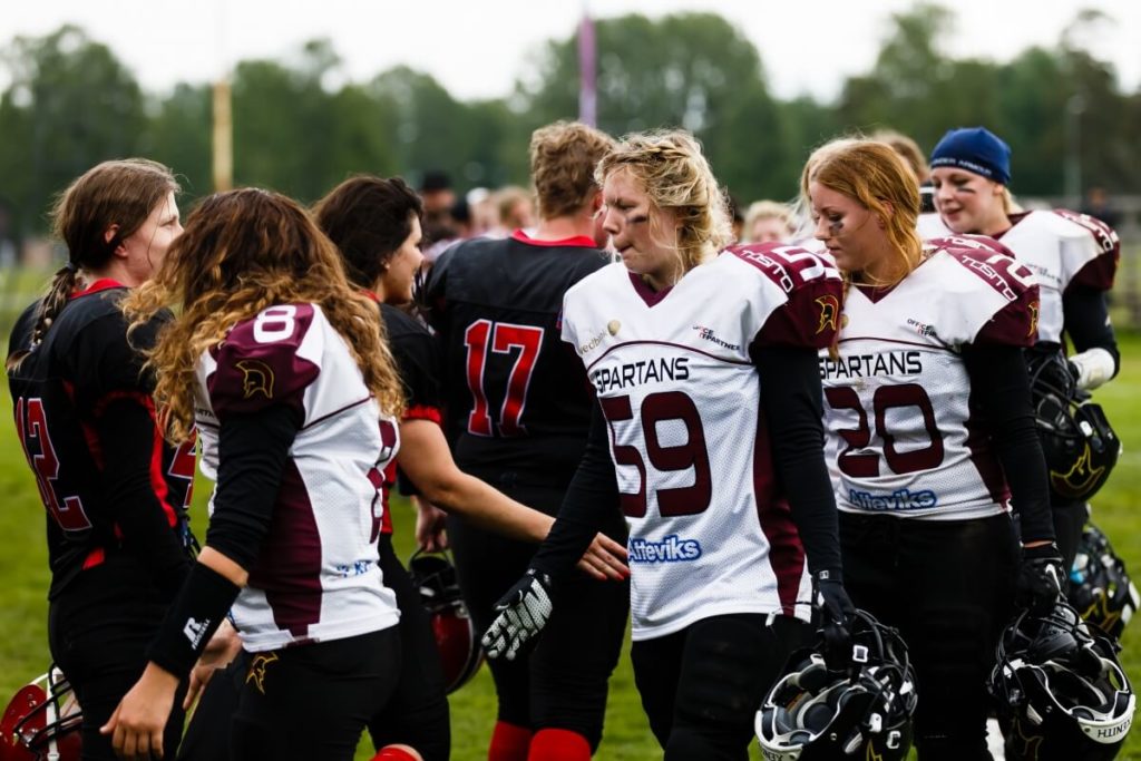 Female football players huddled together on grassy field