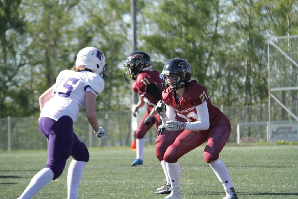Female football players lined up on green turf.