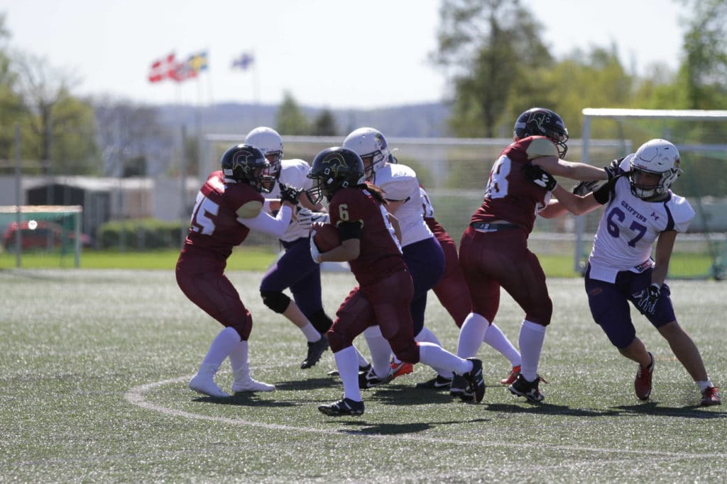 Maroon and white teams playing tackle football fiercely.