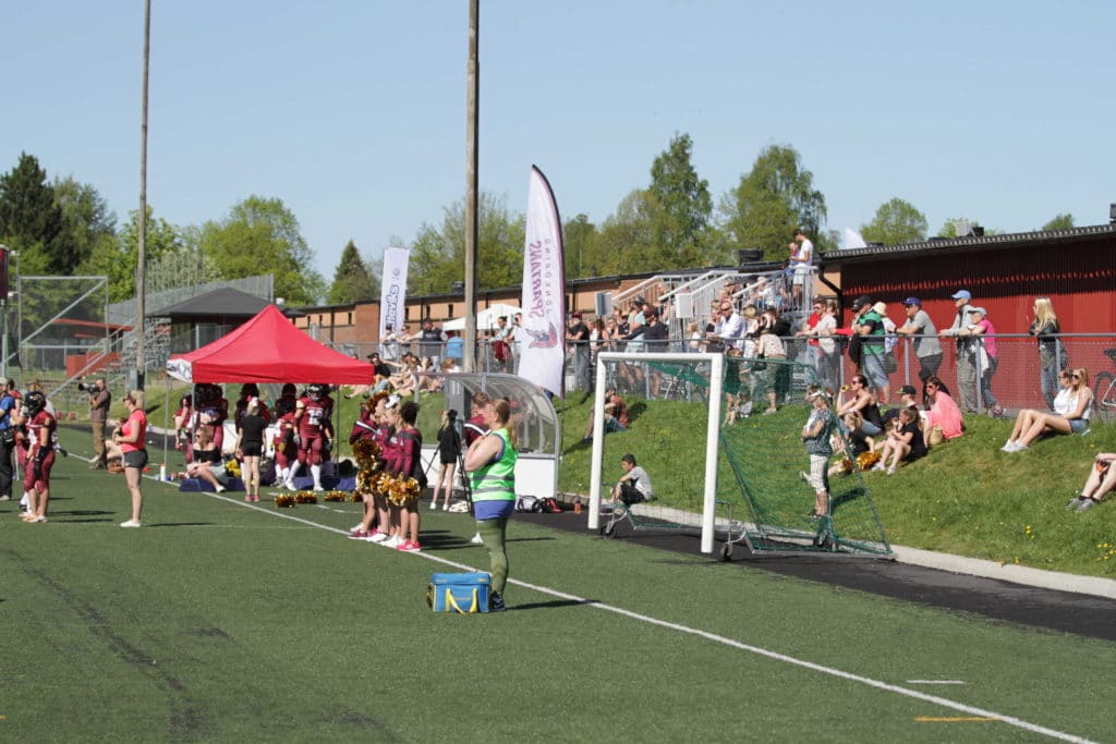 Outdoor sports field with fans and cheerleaders.