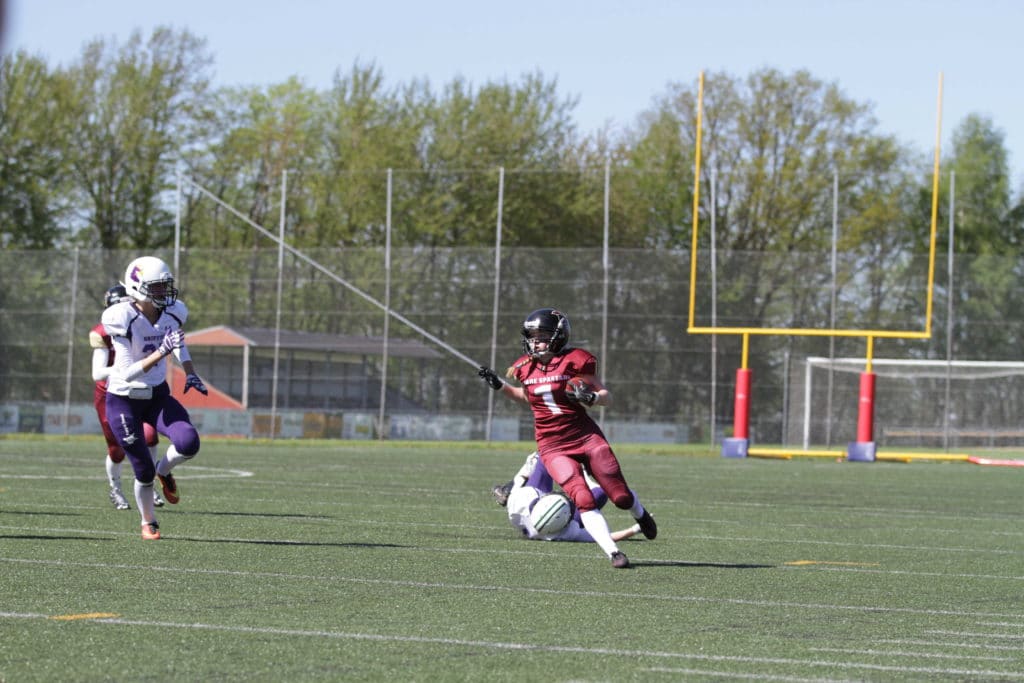 Football player escapes tackle on sunny green field