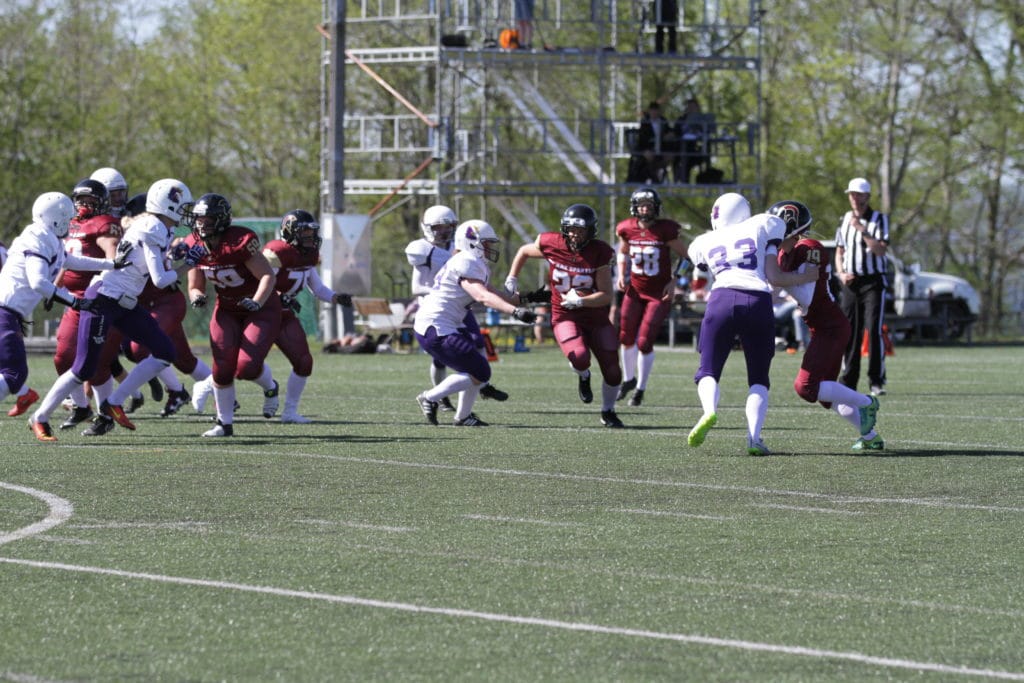 Football players running hard during sunny outdoor game.
